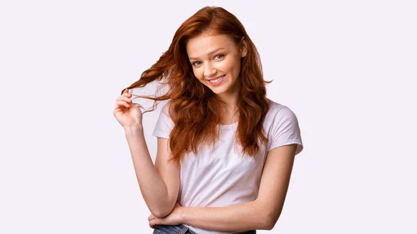 Pretty Millennial dívka hrát s červenými vlasy pózu ve studiu — Stock fotografie