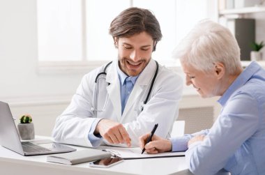 Neşeli yaşlı kadın hastanede doktorla sözleşme imzalıyor.