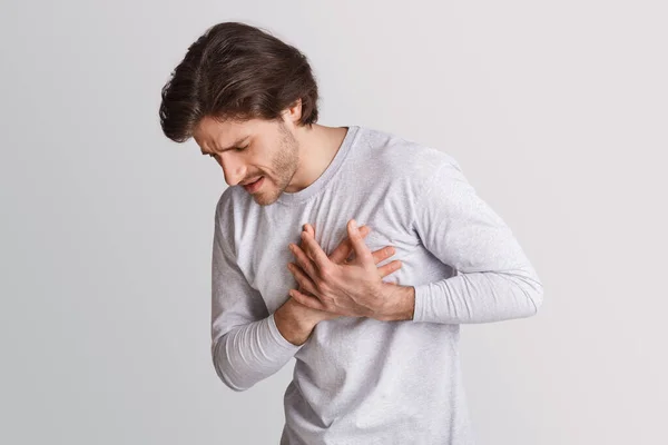 Ataque cardíaco em tenra idade. Homem pressiona as mãos para dor no peito e expressão facial — Fotografia de Stock