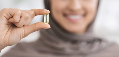 Diyet takviyesi. Türbanlı Tanınmayan Müslüman Kadın 'ın Elinde Şeffaf Vitamin Hapları