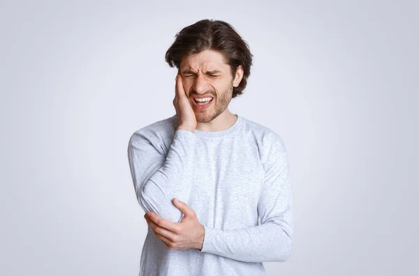 Kraftig smärta i öronen. Man grimaserar och håller sin hand mot ömma punkten — Stockfoto