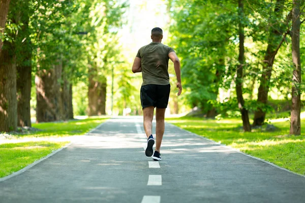 Widok z tyłu Afroamerykańskiego sportowca na torze do joggingu w pięknym parku — Zdjęcie stockowe