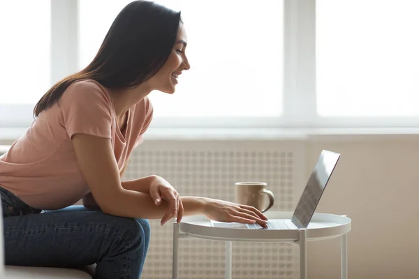 Neşeli kız dizüstü bilgisayar kullanıyor. Evde kahve içip internette geziniyor. — Stok fotoğraf