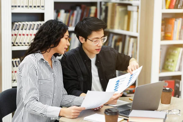 Couple discutant de graphiques et de diagrammes dans la bibliothèque — Photo