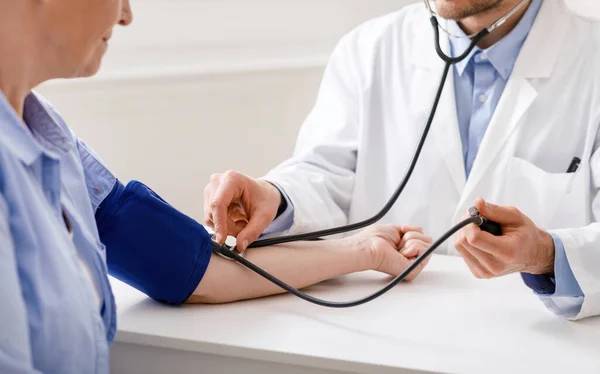 Médico verificando a pressão arterial do paciente sênior durante a visita — Fotografia de Stock