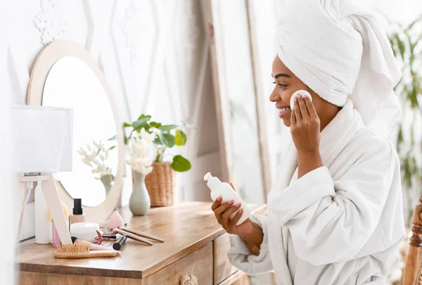 Femme noire nettoyant visage avec lait nettoyant et coton à la maison — Photo