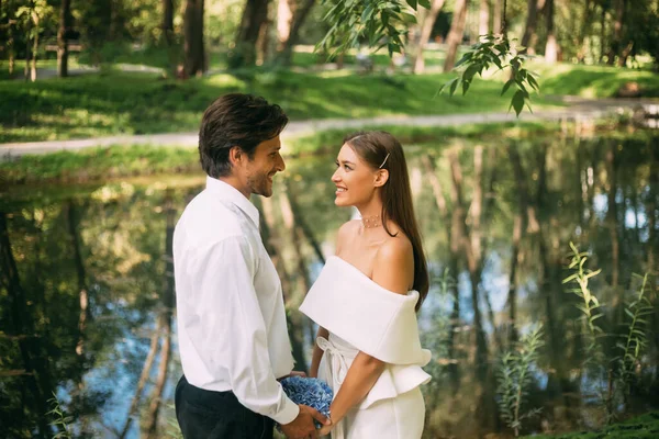 Feliz boda pareja diciendo votos sosteniendo manos de pie en el parque — Foto de Stock