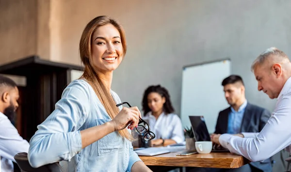 Empresária bem sucedida sentada com funcionários no escritório moderno — Fotografia de Stock