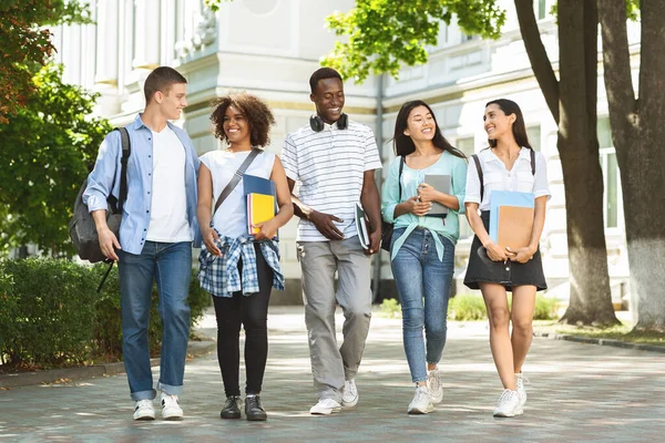 Students communication. Group of college friends walking outdoors in university campus Stock Photo