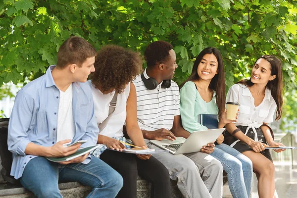 Alegres estudiantes universitarios discutiendo al aire libre mientras descansan entre clases — Foto de Stock