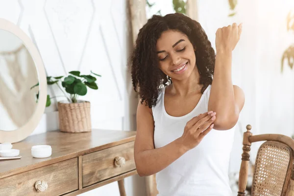 Tratamento da pele sensível. Afro mulher aplicando hidratante creme calmante na zona do cotovelo — Fotografia de Stock