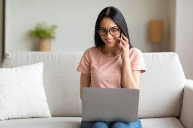 Dizüstü bilgisayarlı bir kadın telefonda konuşuyor.