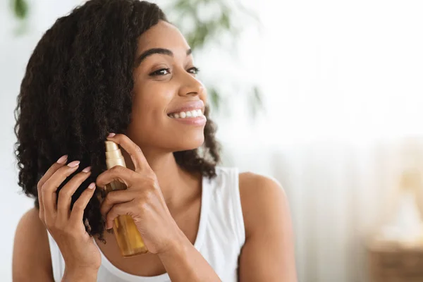 Cuidado del cabello. feliz afro mujer usando aceite para dividir extremos en casa —  Fotos de Stock