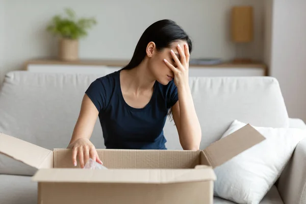 Meisje uitpakken doos gefrustreerd met verkeerde pakket zitten thuis — Stockfoto