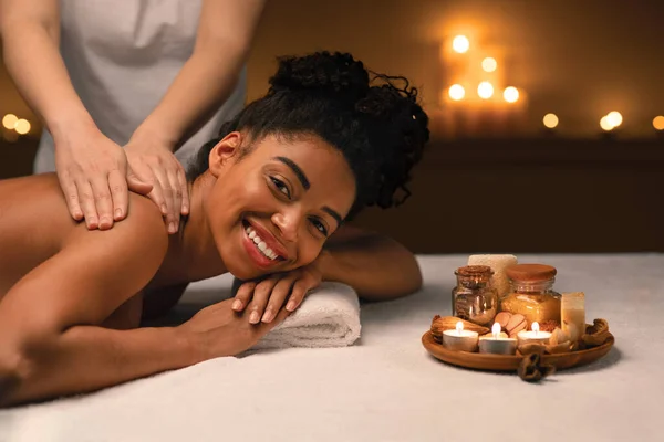 Happy black woman getting healing body massage at spa — Stock Photo, Image