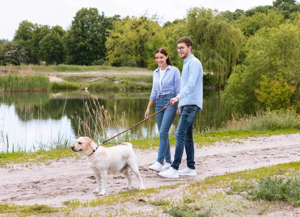 Giovane coppia e golden retriever in esecuzione in campagna — Foto Stock