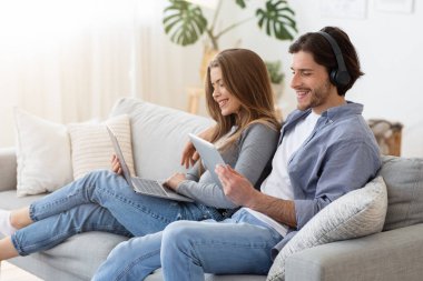 Evdeki koltukta oturan ve alet kullanan bir çift.