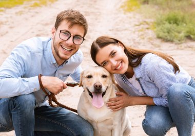 Labradorlarını ovuşturan mutlu genç çiftin portresi.