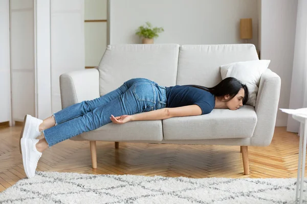 Уставшая девушка лежит на диване и отдыхает дома — стоковое фото