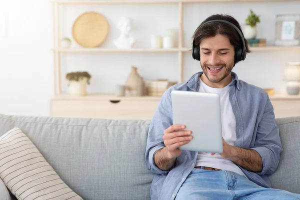 Cheery guy watching funny videos on tablet