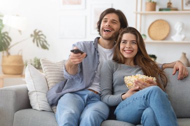 Mutlu adam ve kadın birlikte televizyon izliyor.