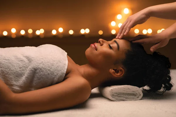 Therapist hands massaging african woman forehead at spa — Stock Photo, Image