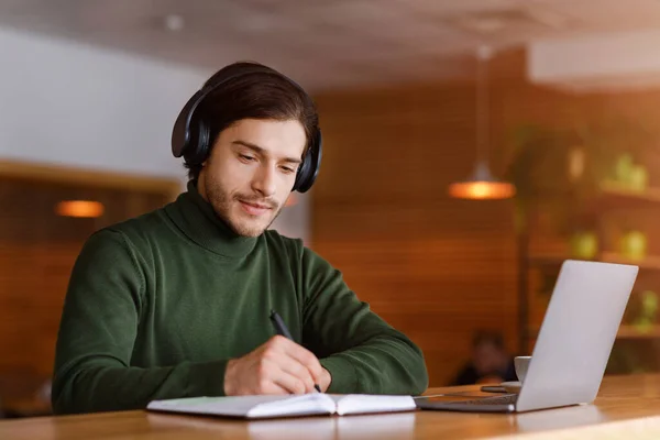 Tipo concentrado con auriculares que estudian en línea, utilizando el ordenador portátil —  Fotos de Stock