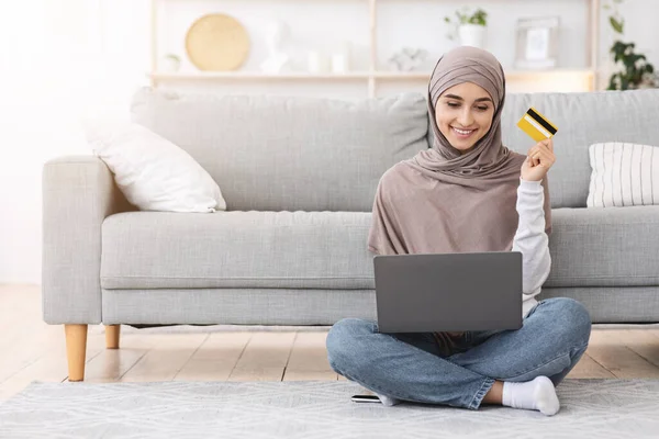 Compras en línea. Chica árabe feliz usando el ordenador portátil y la tarjeta de crédito en casa — Foto de Stock