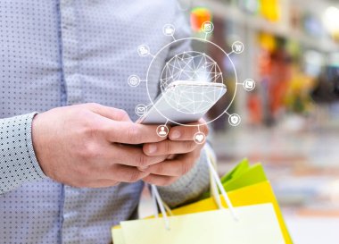 Alışveriş merkezinde çeşitli işlevleri olan cep telefonu kullanan tanınmayan bir adam.