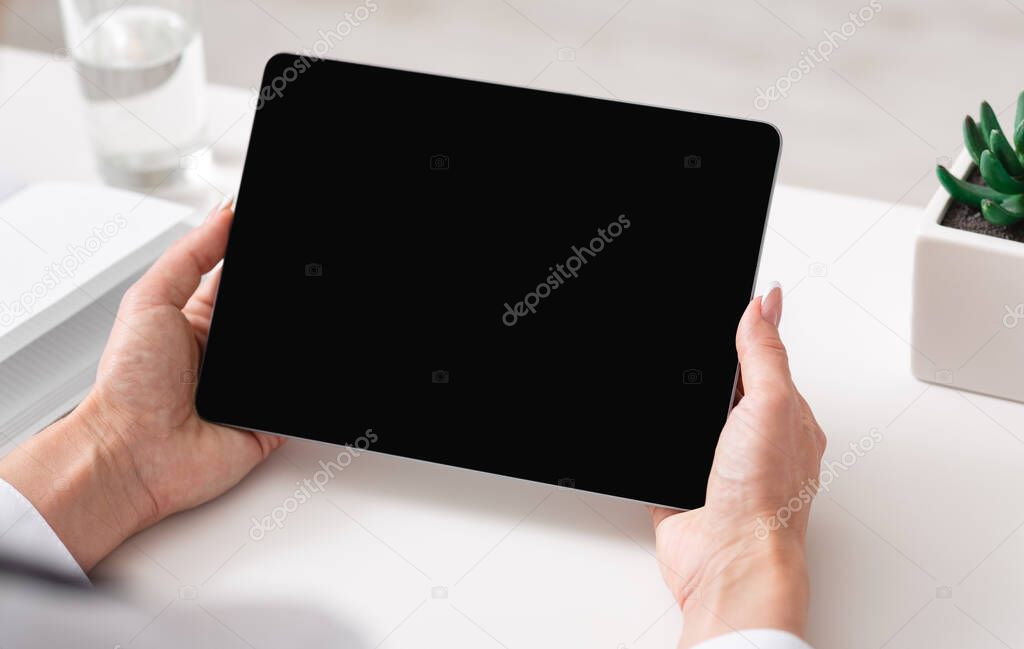 Watching video lesson or online webinar. Woman hands holds tablet with blank screen