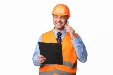 Cep telefonundan konuşan tamirci beyaz arka plandaki kameraya gülümsüyor