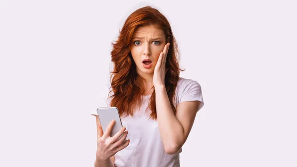 十代の女の子は白い背景の上に恥ずかしいメッセージを読んで携帯電話を保持 — ストック写真