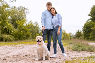 Tatlı bir çift ve Golden Retriever kırsalda yürüyor.