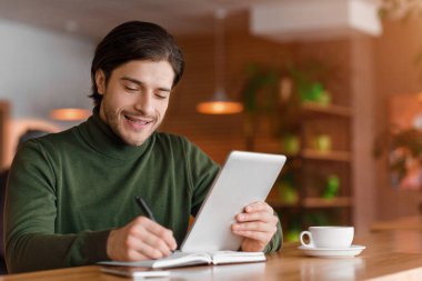 Girişimci gününü planlıyor, not alıyor, dijital tablet kullanıyor.