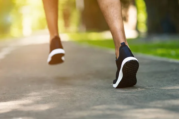 Unerkennbarer Schwarzer in Sportschuhen joggt an sonnigem Morgen im Stadtpark, Nahaufnahme — Stockfoto