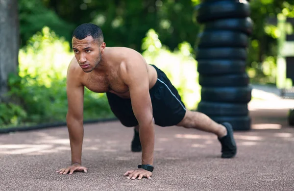 Millennial zwarte man doen push-ups op asfalt weg in het park in de ochtend — Stockfoto