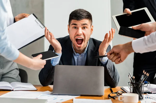 Empresario gritando estresado por múltiples tareas sentado en la oficina moderna — Foto de Stock