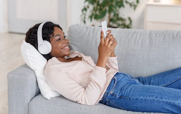 Ragazza nera che ama ascoltare musica su smartphone con cuffie wireless a casa — Foto Stock
