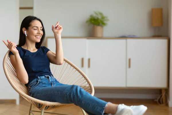 Ontspannen meisje luisteren muziek zitten in gezellige fauteuil thuis — Stockfoto