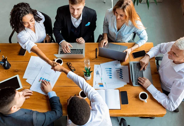 Compañeros de trabajo estrechando las manos durante la reunión sentados en una oficina moderna, vista superior — Foto de Stock