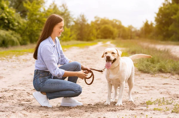 Leende kvinna och hennes gyllene retriever går utomhus — Stockfoto