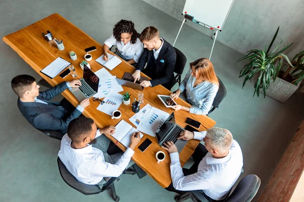 Συνάδελφοι μιλώντας συνεδρίαση με Gadgets Κατά τη διάρκεια της συνεδρίασης στο γραφείο, υψηλής γωνίας — Φωτογραφία Αρχείου
