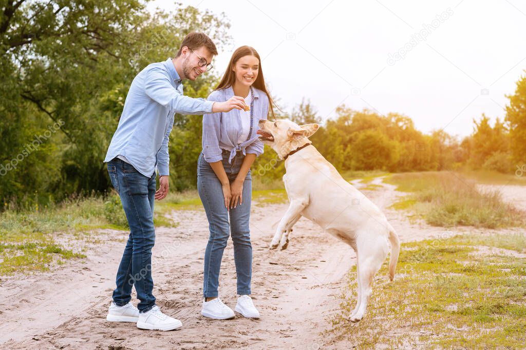 Young couple giving a treat to their happy dog