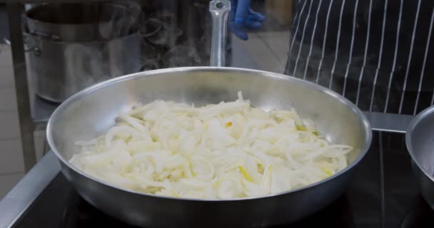 Лук жареный в горячей сковороде на кухне вблизи — стоковое видео