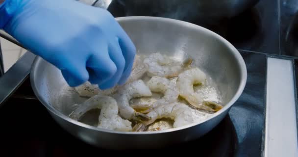 Закрыть шеф-повара, класть свежие креветки в сковородку — стоковое видео