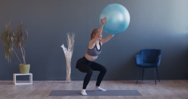 Młoda sportowe kobieta robi przysiady z fitball w ręce — Wideo stockowe