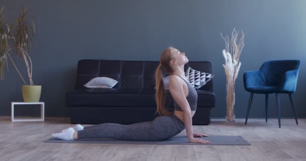 Ung flicka övar yoga, demonstrerar kobra poserar hemma — Stockvideo