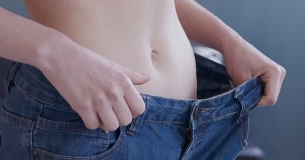 Büyük kot pantolon giyen zayıf kız, kilo kaybı sonucu. — Stok video