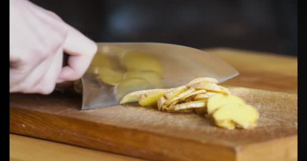Mulher cortando raiz de gengibre fresco na mesa da cozinha, close-up — Vídeo de Stock