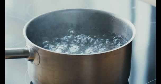 Metalen pan met hete vloeistof op keukenfornuis, close-up — Stockvideo